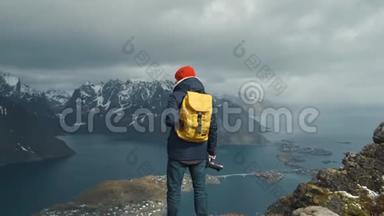 摄影师男带黄色背包，站在山顶自然.. 冒险旅行的概念。 挪威